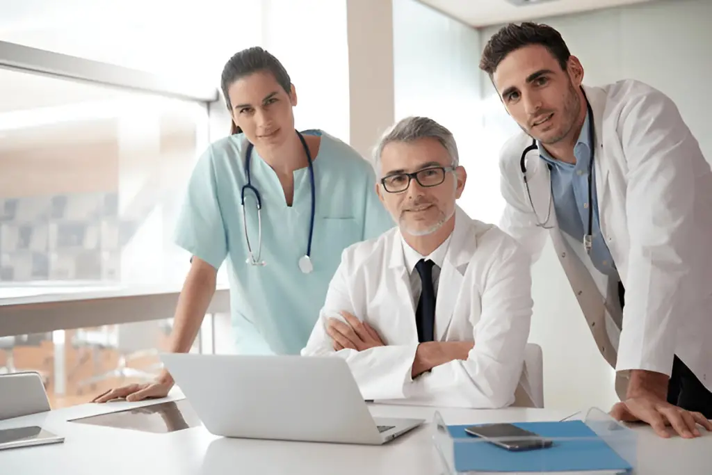 Smiling medical team at laptop.