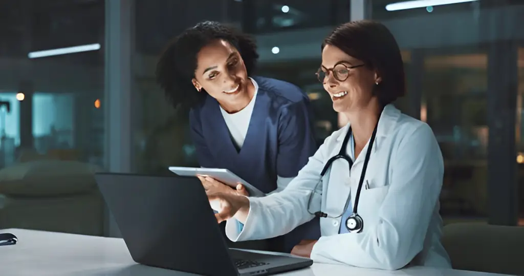 Doctors reviewing laptop late at night.