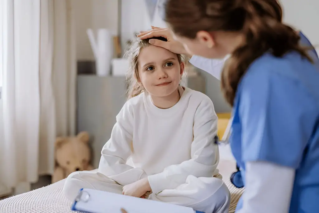 Nurse checks girl's forehead temperature.