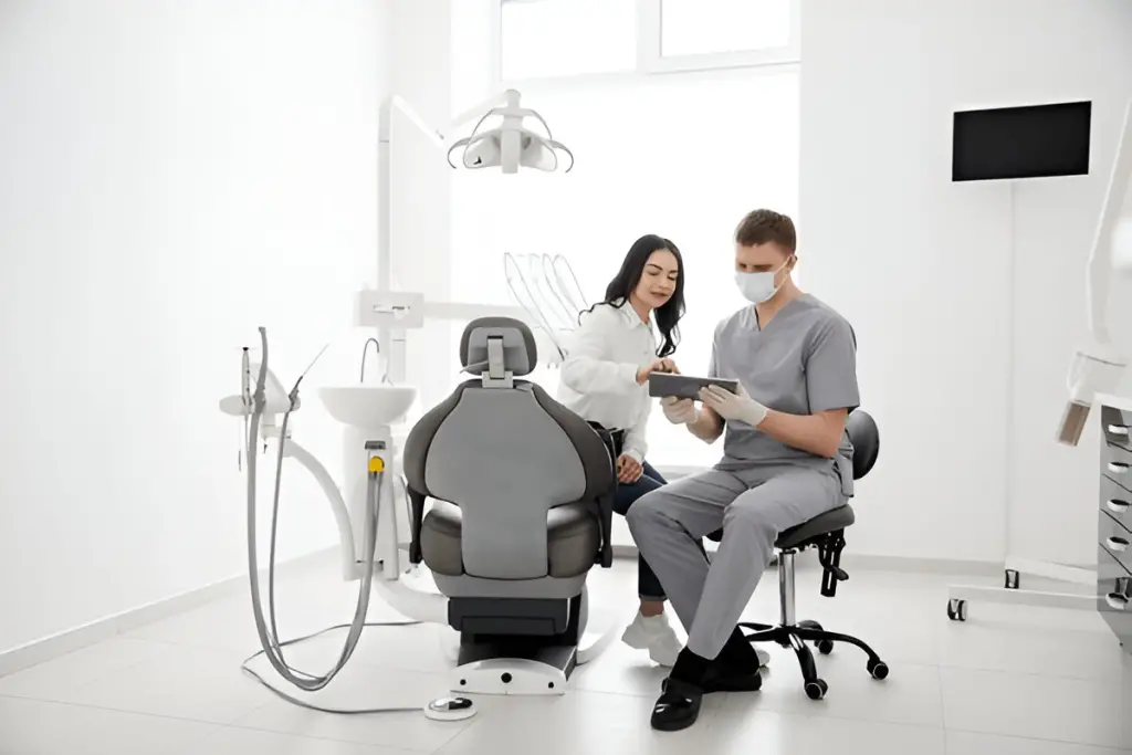 Dentist shows woman tablet in clinic.