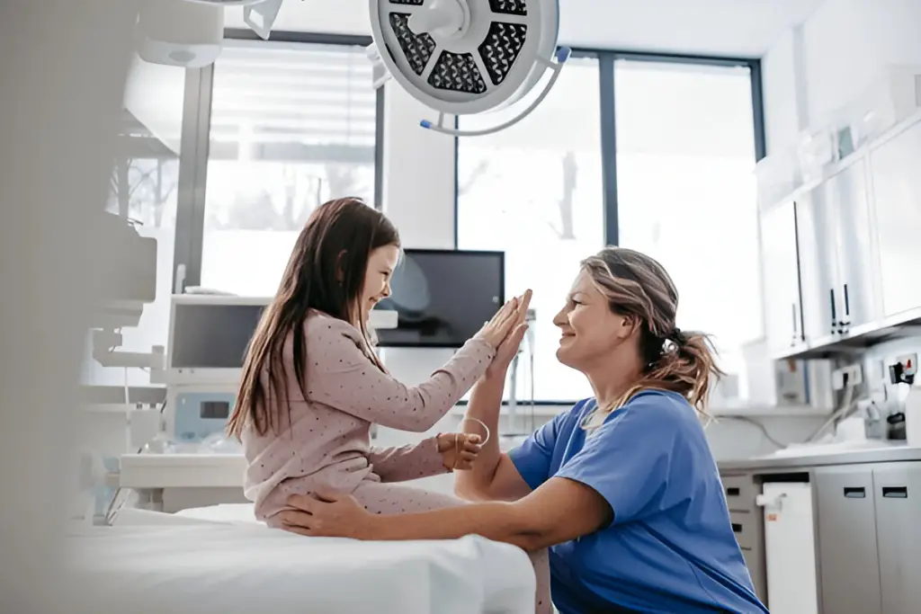 Nurse gives girl high five on exam table