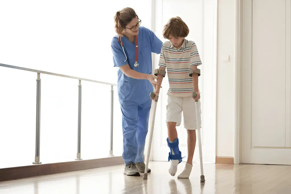 Pediatric nurse helping boy walk with crutches