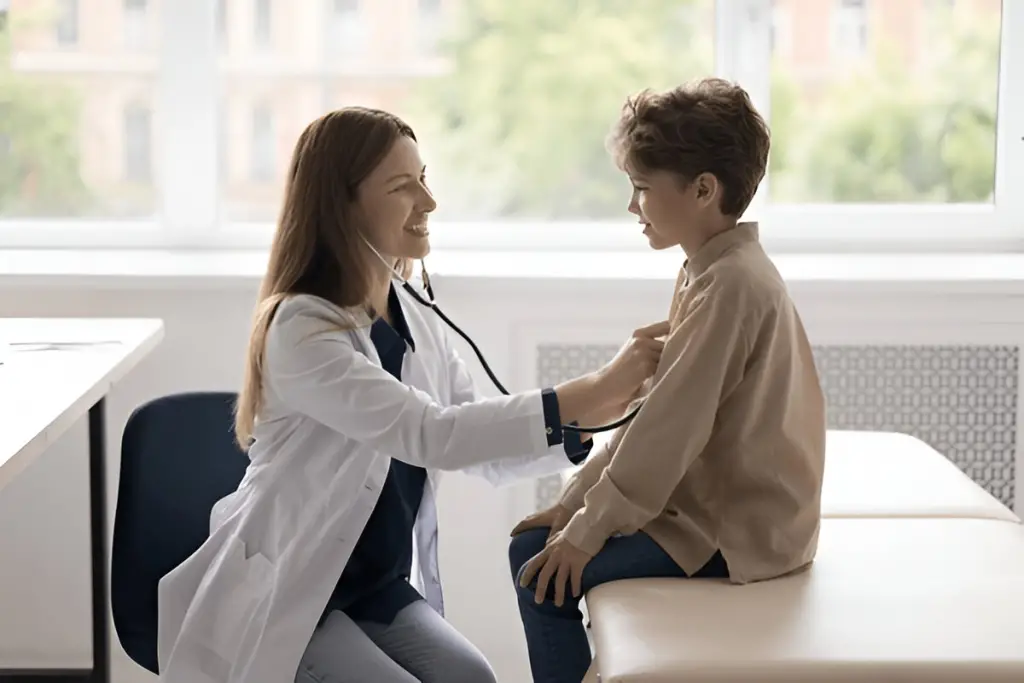 Female doctor listens to young boy's chest