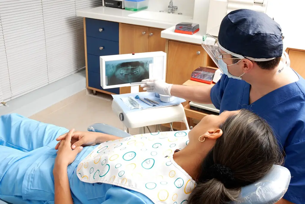 Dentist shows patient dental X-ray.