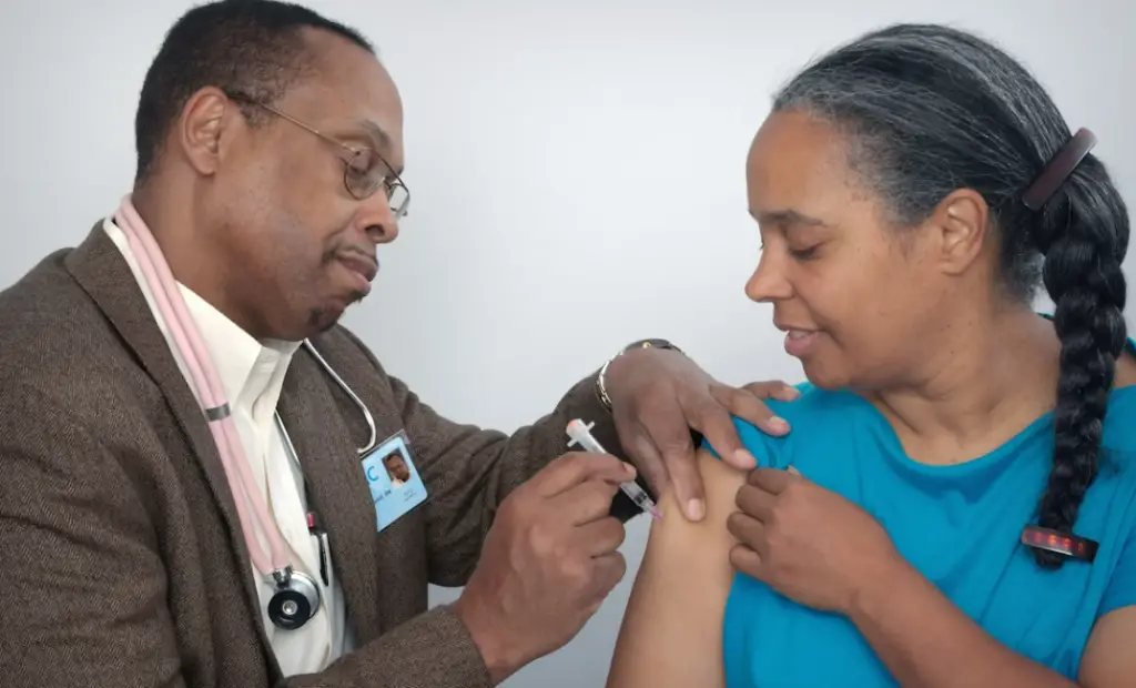 Doctor giving woman a vaccine.