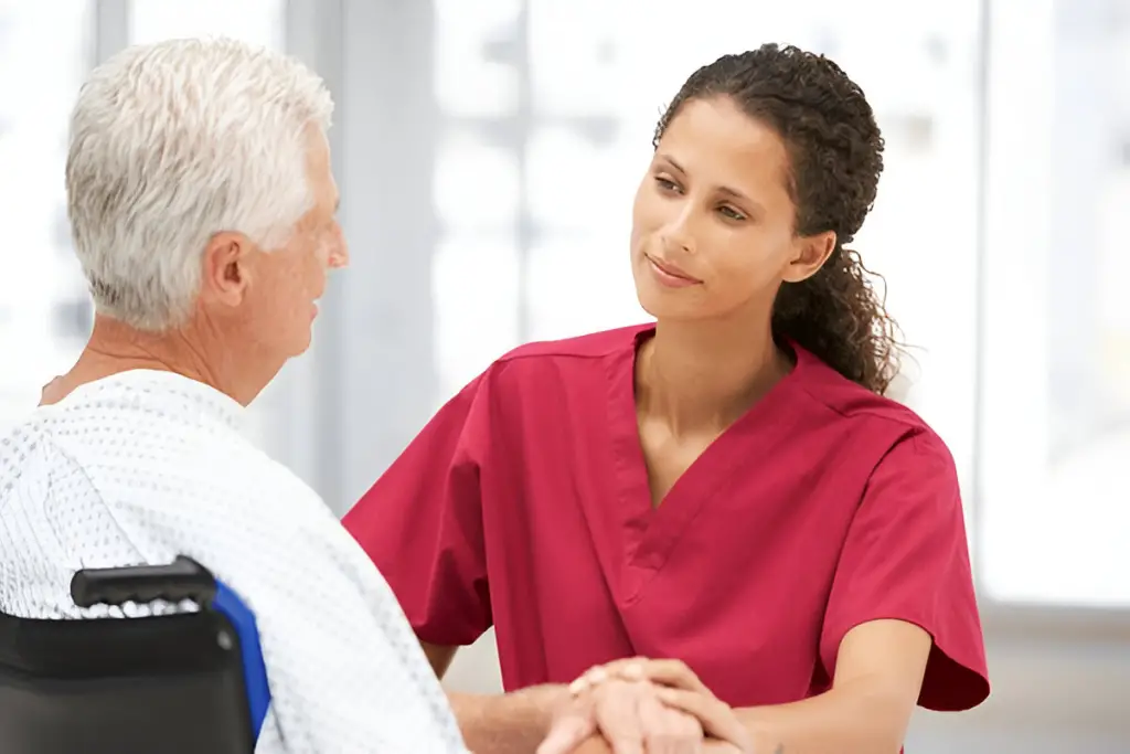 Nurse comforting senior patient in wheelchair.